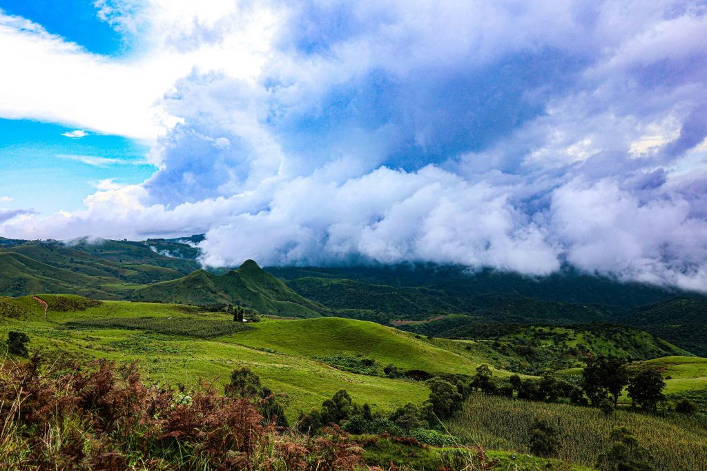 Lush green Mambilla Plateau under dramatic cloudy skies in Taraba, Nigeria.