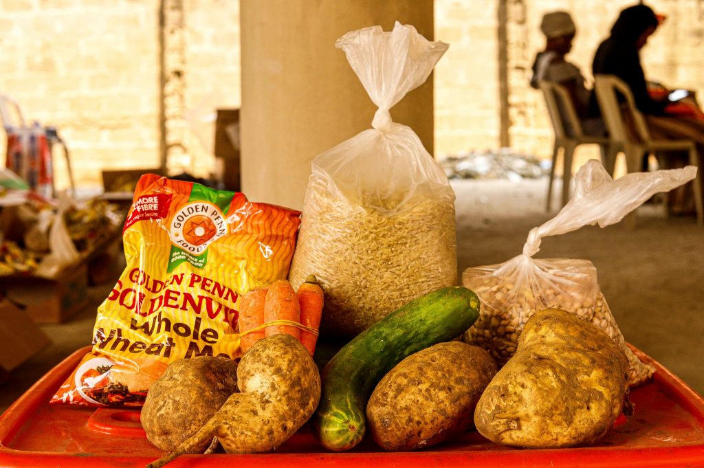Variety of fresh vegetables and packaged food on a market table indoors.