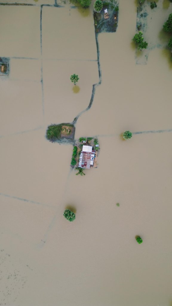 Drone aerial view of inundated farm fields with a house in Krong Stueng Saen, Cambodia.